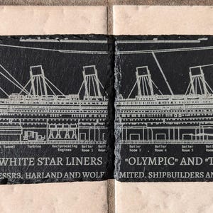 May include: Four black slate coasters with white engraved images of the RMS Titanic and Olympic ships. The coasters feature the text "The White Star Liners" and "RMS Titanic" along with construction details and dates.