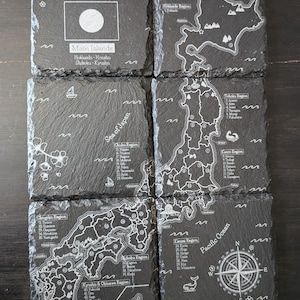 May include: A set of six square black slate coasters featuring white laser-engraved maps of Japan. The designs include the Japanese flag, regional maps of Hokkaido, Tohoku, Kanto, Chubu, Chugoku, Shikoku, Kyushu, and Okinawa, plus a compass rose.