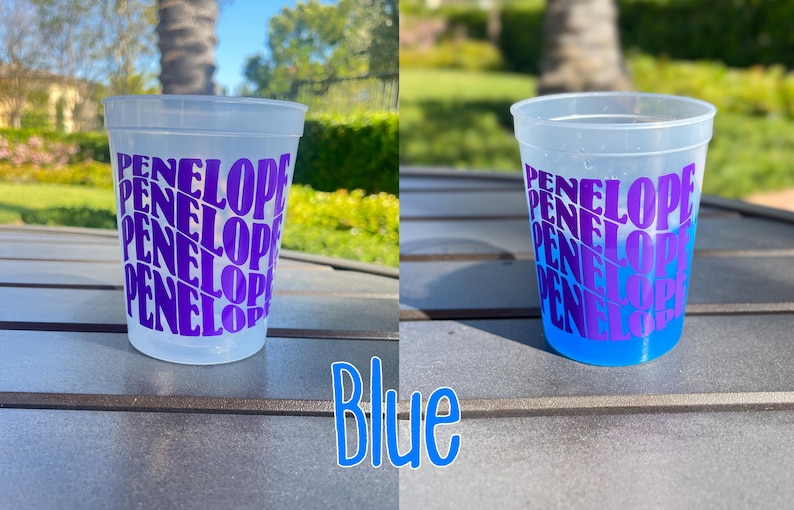 May include: A frosted plastic cup featuring the name Penelope printed in a repeating, wavy purple font. The cup is shown empty on the left and filled with a bright blue liquid on the right, demonstrating a color-changing effect when cold.