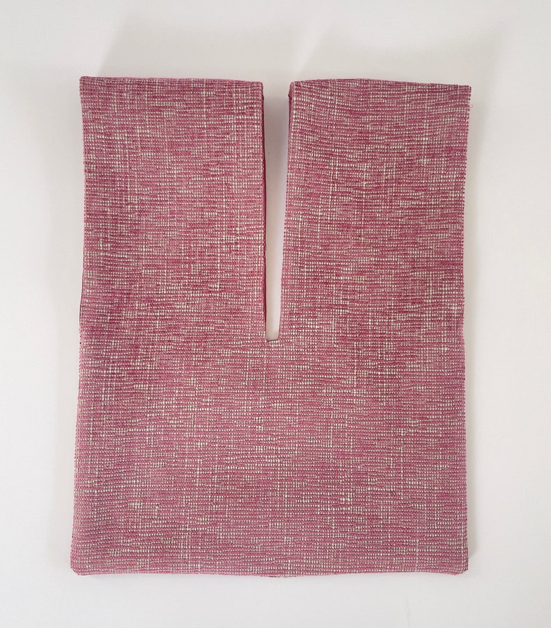 May include: A pink fabric bag with a V-shaped opening at the top. The fabric has a subtle textured pattern.