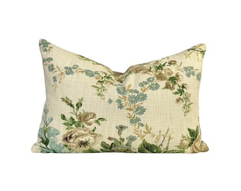 May include: A cream-colored pillow with a floral pattern featuring blue, green, and brown flowers. The pillow is made of a soft, textured fabric.