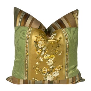 May include: A decorative pillow with a patchwork design featuring green, gold, and brown fabrics. The center panel features a floral pattern with embroidered flowers.