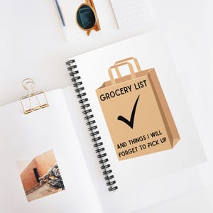 May include: A spiral-bound notebook with a brown paper bag graphic that says "Grocery List" and "And Things I Will Forget To Pick Up". A gold paper clip and sunglasses are also visible.