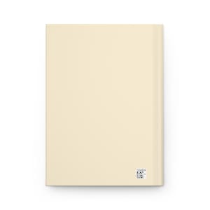 May include: A cream-colored journal with a smooth cover. The spine is visible on the right side. A small black and white barcode and a series of numbers are printed near the bottom right corner.