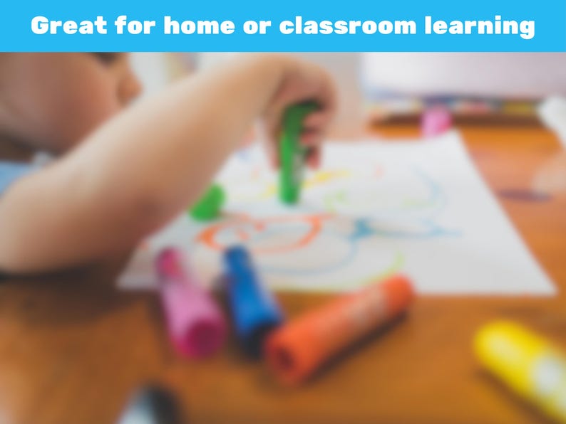 May include: A child's hand is holding a green crayon over a white paper with colorful drawings. Several crayons in pink, blue, orange, and yellow are scattered on a wooden table. The text "Great for home or classroom learning" is in a blue banner.