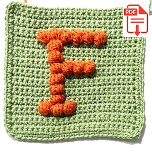May include: A square crochet patch in light sage green featuring a textured, raised letter F in bright orange yarn. The letter is constructed from a series of small, rounded bobble stitches that stand out against the flat, single crochet background.