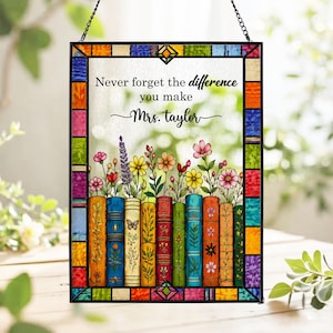 May include: Stained glass panel with a colorful border and a chain for hanging. The panel features the text "Never forget the difference you make Mrs. Taylor" above a row of books with flowers.