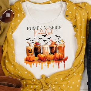 Könnte beinhalten: Weißes T-Shirt mit einem Grafikdesign aus Kürbisgewürzgetränken, Kürbissen und Fledermäusen. Der Text "Pumpkin Spice Kinda Girl" ist auf das Shirt gedruckt.