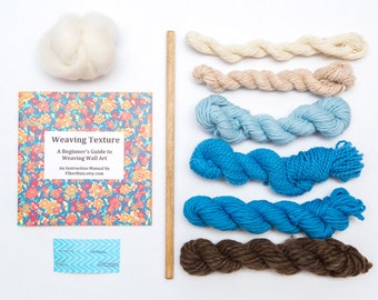 May include: Weaving Texture: A Beginner's Guide to Weaving Wall Art, an instruction manual by FiberHatsEtsy.com, with a wooden dowel, white wool roving, and six skeins of yarn in shades of white, beige, light blue, blue, turquoise, and brown.