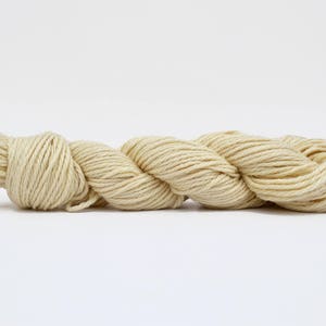 Könnte beinhalten: Ein Knäuel naturweißes Garn, gedreht und bereit zum Stricken oder Häkeln.