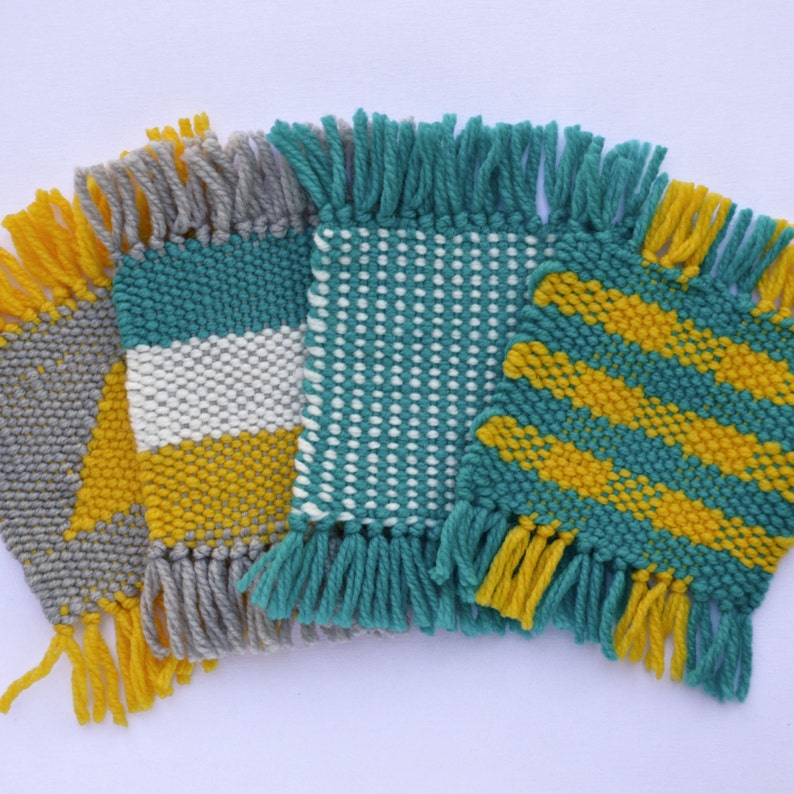 Puede incluir: Tres posavasos tejidos con flecos. Los posavasos est&aacute;n hechos con hilo turquesa, blanco y amarillo. Los patrones incluyen rayas, lunares y un dise&ntilde;o de chevron.