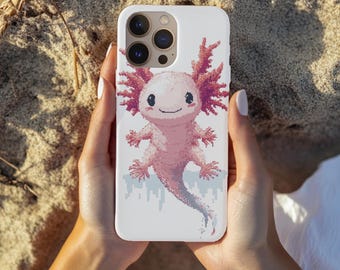 Peut inclure: Une coque de smartphone blanche ornée d'une illustration en pixel art représentant un axolotl rose avec des branchies plumeuses. L'axolotl est centré au dos de la coque, qui présente une découpe pour un triple capteur photo en haut à gauche.