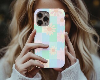 Puede incluir: Una funda para smartphone con un patrón de tablero de ajedrez en tonos pastel de azul claro, verde menta y lavanda suave, decorada con ilustraciones de margaritas de color naranja claro y rosa pálido sobre la superficie cuadriculada.