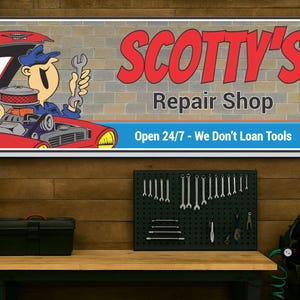 Personalized repair garage sign featuring cartoon mechanic working on a red car, displayed against a workshop wall with garage elements in the background.
