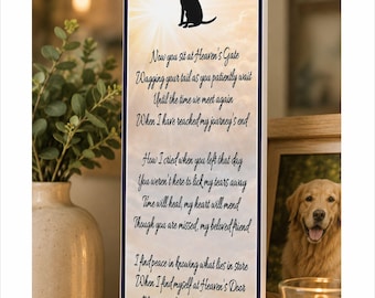 May include: A rectangular vertical sign with a dark border featuring a black silhouette of a winged dog with a halo. The background is a soft yellow and white sky. The text reads: Now you sit at Heaven's Gate, Wagging your tail as you patiently wait, Until the time we meet again, When I have reached my journey's end. How I cried when you left that day, You weren't here to lick my tears away, Time will heal, my heart will mend, Though you are missed, my beloved friend. I find peace in knowing what lies in store, When I find myself at Heaven's Door, My tears of joy shall fall that day, When you run to me to frolic and play, And gently lick my tears away. Four black paw prints are at the bottom.