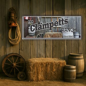 May include: A rustic wooden sign with the text "The Clampetts Ranch Since 2004". The sign is decorated with old-fashioned farm tools and barrels.