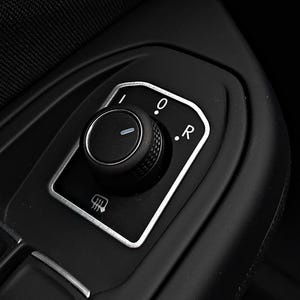 Puede incluir: Un detalle interior de un coche negro con un borde plateado alrededor de una perilla negra con un indicador blanco. La perilla tiene un '0' y una 'R' blancas. La perilla se utiliza para ajustar los espejos laterales.