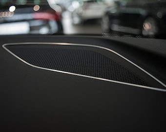 May include: Close-up of a black car interior with a silver speaker grille.