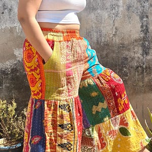 Puede incluir: Pantalones de patchwork coloridos con diseño de pernera ancha. Los pantalones presentan una variedad de patrones y colores, incluyendo rojo, amarillo, azul y naranja. Los pantalones se combinan con un top corto blanco. Los pantalones tienen bolsillos.