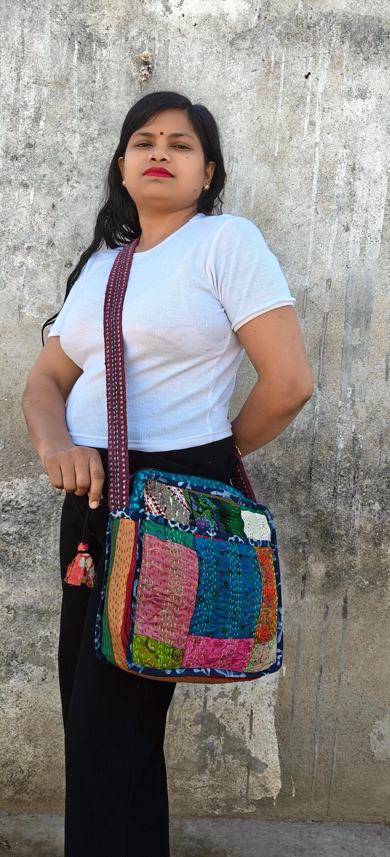 Pode incluir: Uma bolsa tiracolo quadrada com um design de patchwork de v&aacute;rios quadrados de tecido coloridos em tons de azul, rosa, amarelo e verde, acentuada com bordados de ponto corrido vis&iacute;veis e uma al&ccedil;a de ombro tecida e estampada.