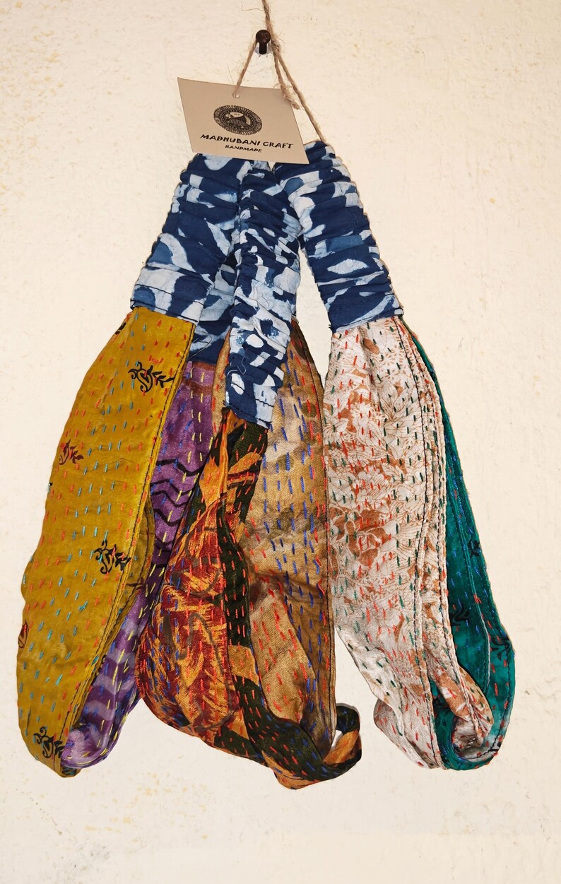 Peut inclure: Plusieurs articles en tissu faits &agrave; la main, peut-&ecirc;tre des bandeaux ou des &eacute;charpes, suspendus sur un fond blanc. Les tissus pr&eacute;sentent divers motifs, dont des motifs floraux et tie-dye, avec des couleurs comme le jaune, le bleu et l'orange. L'&eacute;tiquette indique "MADHUBANI CRAFT HANDMADE."
