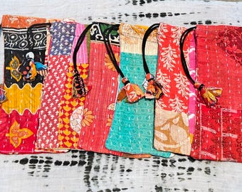 Pode incluir: Uma coleção de bolsas de tecido patchwork coloridas com cordões pretos e detalhes de borlas. As bolsas apresentam vários padrões, incluindo desenhos florais e geométricos, em tons de vermelho, amarelo e azul-petróleo.
