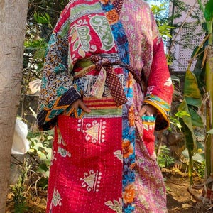 Könnte beinhalten: Kimono-ähnlicher Patchwork-Bademantel in Rot-, Rosa-, Grün- und Blautönen. Der Bademantel hat ein Blumen- und geometrisches Muster mit passendem Gürtel. Der Bademantel wird im Freien getragen.