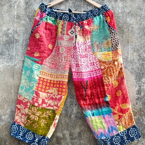 Peut inclure: Pantacourt patchwork multicolore avec taille élastique. Le patchwork présente des tissus variés aux tons de rouge, rose, bleu et vert, avec des motifs floraux et géométriques.
