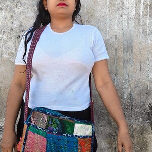 Pode incluir: Uma bolsa tiracolo retangular com um design de patchwork feito de v&aacute;rios quadrados de tecido coloridos com costuras kantha complexas. A bolsa tem uma al&ccedil;a longa estampada e &eacute; usada sobre uma camiseta branca e cal&ccedil;as pretas.