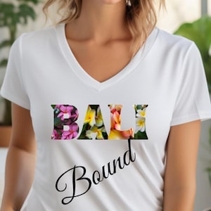 Puede incluir: Camiseta blanca de cuello en V con un diseño floral que deletrea "BALI" y el texto "Bound" debajo.