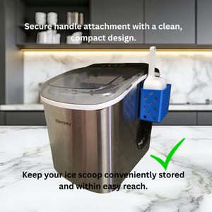Puede incluir: Una máquina de hielo de acero inoxidable con tapa negra y una cesta de almacenamiento de plástico azul unida al lateral. La cesta contiene una pala de hielo de plástico blanco. El texto dice: Secure handle attachment with a clean, compact design.