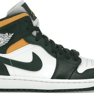 Puede incluir: Zapatilla alta en blanco, verde oscuro y amarillo dorado. La zapatilla presenta una puntera blanca, un logotipo de swoosh verde oscuro y una entresuela blanca. El logotipo de Air Jordan es visible en el lateral.