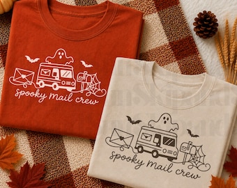 Puede incluir: Dos camisetas, una de color naranja óxido y otra crema, cada una con un gráfico blanco o negro de un camión de correo con un fantasma encima, un buzón con una telaraña, murciélagos, un sobre y el texto spooky mail crew en letra cursiva.