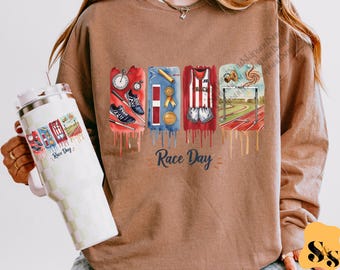 May include: A brown sweatshirt with a graphic print of a running track, a runner, a medal, a stopwatch, and running shoes. The text "Race Day" is printed on the sweatshirt.
