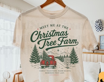 Puede incluir: Una camiseta de color crema con un gráfico de una camioneta roja que transporta un árbol de Navidad. El texto dice: MEET ME AT THE CHRISTMAS TREE FARM, FRESH CUT PINE-FIR-SPRUCE, y FAMILY TRADITIONS. WARM HEARTS. MEMORIES THAT LAST.