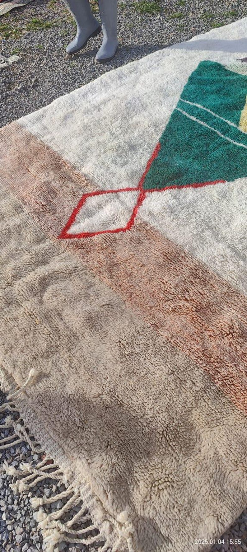May include: A white, beige, and green rug with a geometric pattern. The rug has a fringe border and is made of a soft, fluffy material.