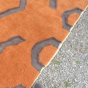 May include: A close-up of a brown and gray patterned rug with a fuzzy texture. The rug is folded in half and the edge is visible.