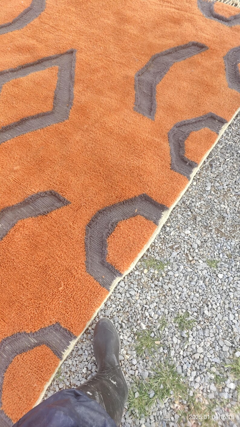 May include: A close-up of a brown and gray patterned rug with a fuzzy texture. The rug is folded in half and the edge is visible.