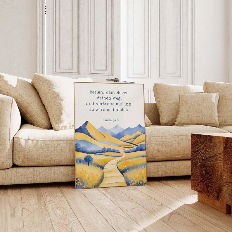 May include: A framed art print featuring a watercolor landscape with yellow and blue mountains, a path, and text in German. The text reads "Befiehl dem Herrn deinen Weg, und vertraue auf ihn, so wird er handeln. Psalm 37.5."