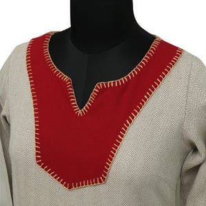 A close-up of the neckline of a light gray herringbone dress with a red yoke, featuring visible light beige stitching around the red fabric.
