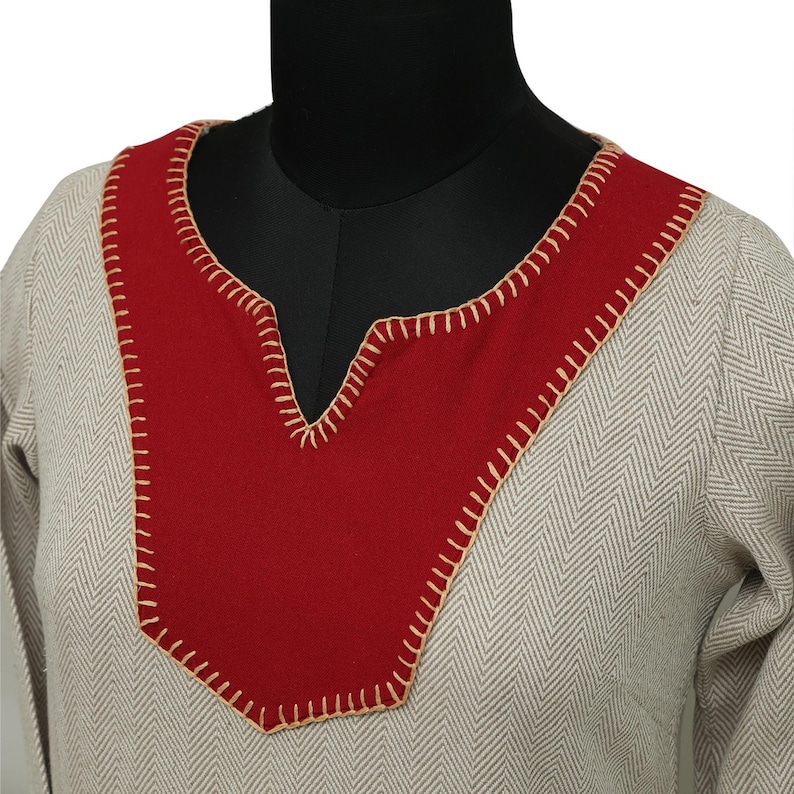 A close-up of the neckline of a light gray herringbone dress with a red yoke, featuring visible light beige stitching around the red fabric.