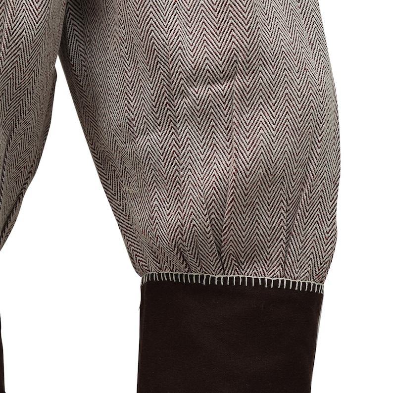 May include: Close-up of the cuff of a brown and white herringbone patterned jacket with a brown fabric cuff.