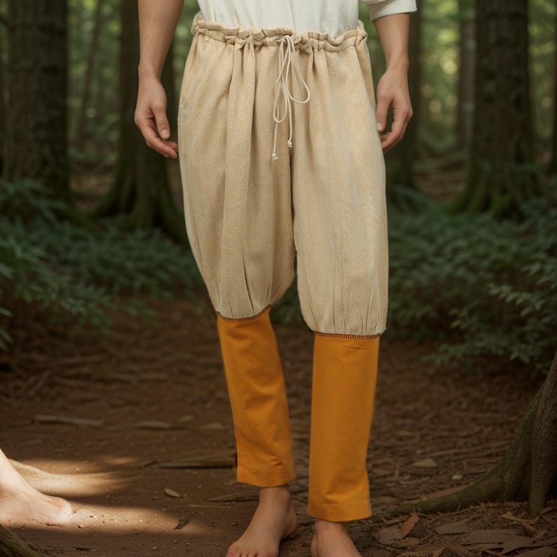 May include: Beige linen pants with a drawstring waist and orange fabric trim at the bottom. The pants are gathered at the knees.