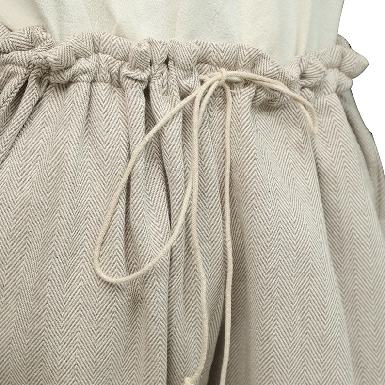 May include: A pair of beige pants with a herringbone pattern and a drawstring waist.