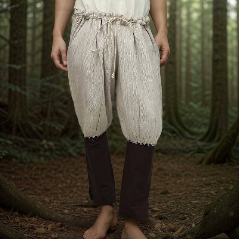 May include: A pair of beige linen pants with a drawstring waist and dark brown fabric at the bottom of the legs.