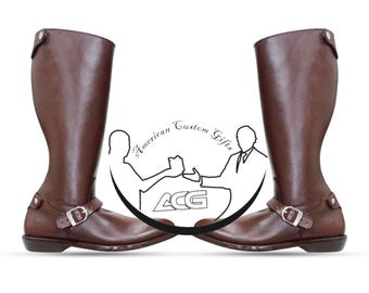 May include: A pair of brown leather riding boots with a buckle strap and a pointed toe. The boots are on a white background with a logo that says "American Custom Gifts".