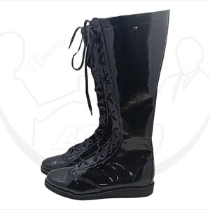 May include: A pair of black, knee-high boots with a glossy patent leather finish. The boots feature a lace-up design with black laces and a rounded toe. The boots are designed for a sleek, polished look.