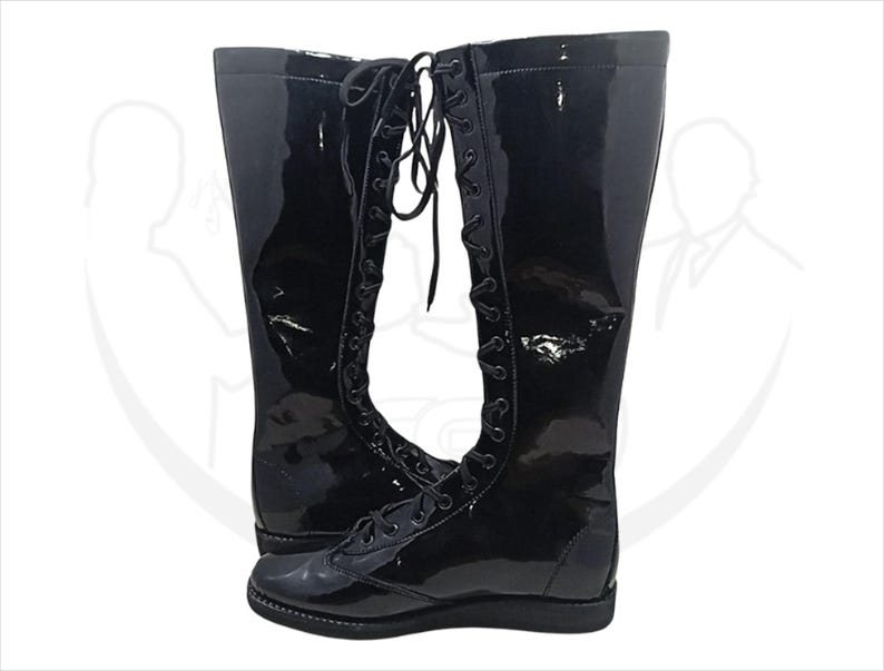 May include: A pair of tall, black, glossy boots with a lace-up design. The boots have a shiny, patent leather-like finish and a flat sole. The laces run up the front of the boots, adding a classic touch to the footwear.