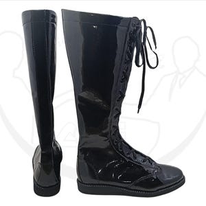 May include: Pair of tall, black, glossy boots. The boots are knee-high with a lace-up design and a rounded toe. The material appears to be patent leather or a similar shiny material. The boots are displayed against a white background.