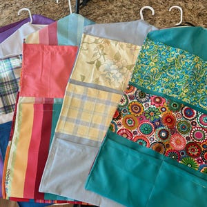 May include: Four hanging fabric organizers with different patterns. The organizers are made of patchwork fabric and have multiple pockets. The organizers are in various colors, including purple, pink, blue, yellow, green, and white.